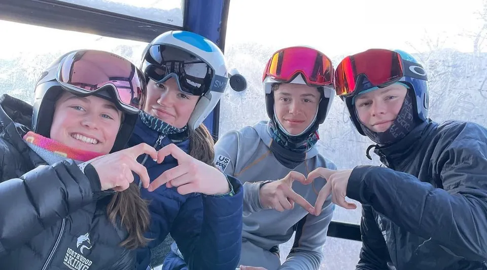 Alcuni studenti della Northwood School indossano l'attrezzatura da sci e formano simboli a forma di cuore con le mani davanti a una finestra innevata.