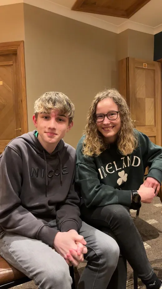 Chico y chica sentados en el salón de la casa, ella con una sudadera de Irlanda