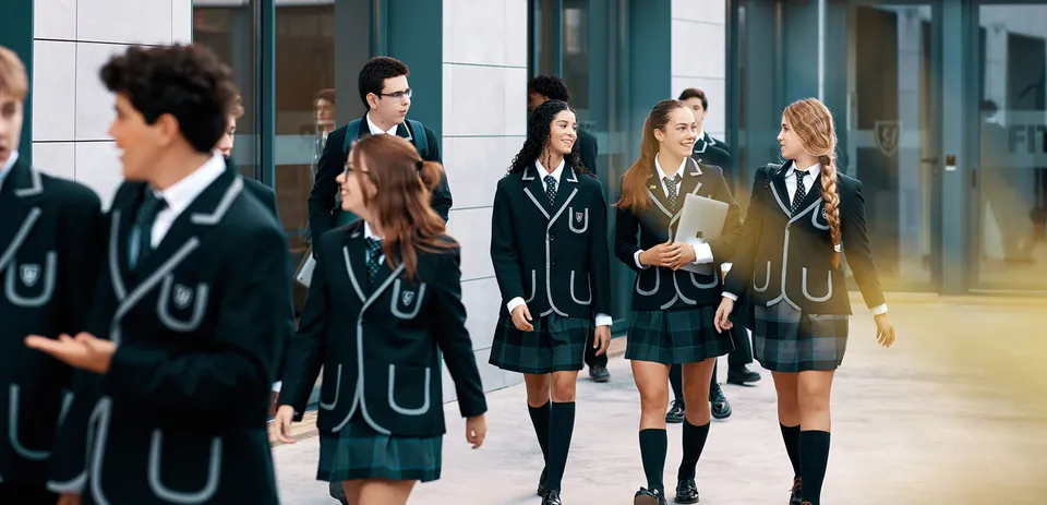 Un gruppo di studenti della Yago School cammina insieme nel campus scolastico con un edificio moderno sullo sfondo.