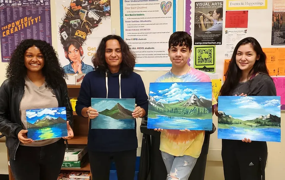 Studenti della Mallard Creek High School mostrano colorati dipinti paesaggistici nell'aula d'arte.