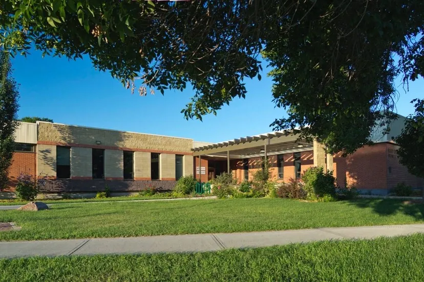 L'edificio moderno in mattoni con ingresso coperto delle Red Deer Public Schools è circondato da un prato ben curato e alberi.