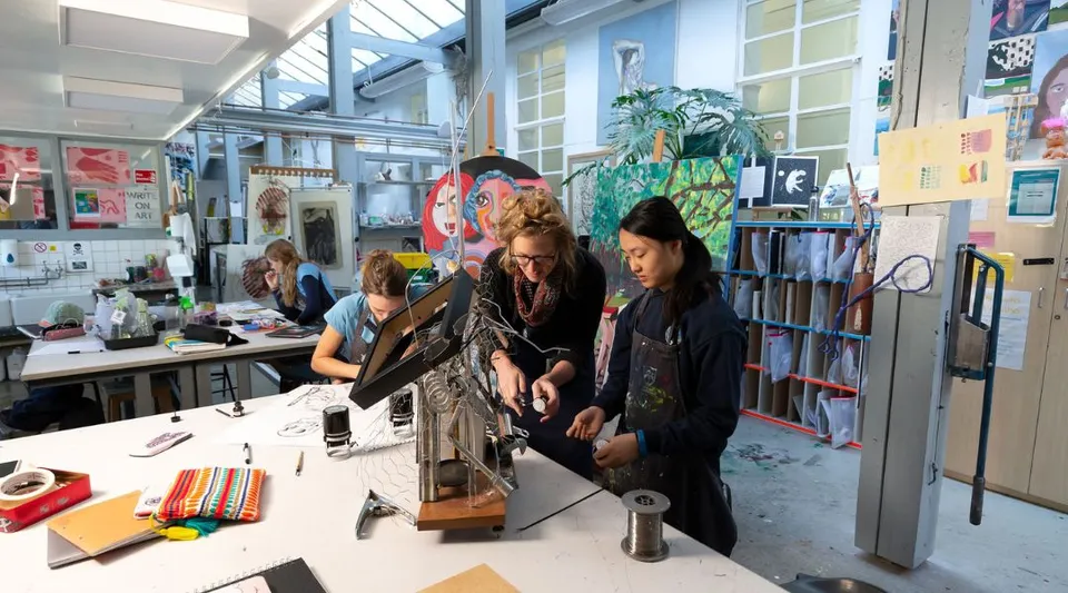Studenti della St. Mary’s Calne lavorano insieme in uno studio d'arte con vari materiali e opere d'arte alle pareti.