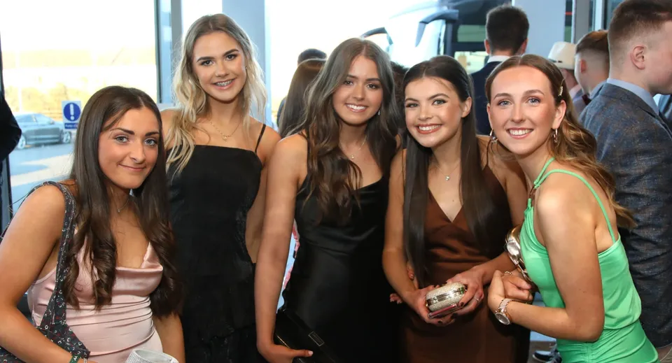 Un gruppo di giovani studentesse della Royal Masonic School for Girls posa insieme davanti a una parete di vetro.