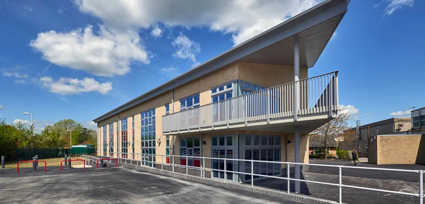 L'edificio scolastico moderno a più piani della Fulston Manor School con ampie finestre e balcone sotto un cielo blu.