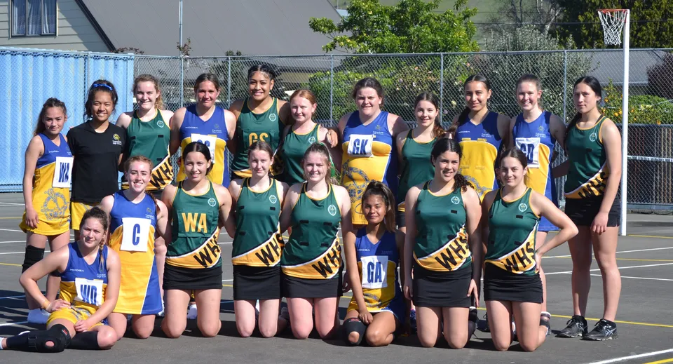 Un gruppo di studentesse del Whanganui City College posa in uniformi sportive su un campo da basket all'aperto.