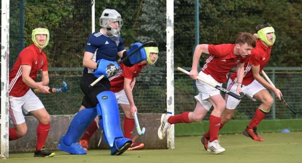 Studenti della Villiers School giocano una partita di hockey su prato su un campo circondato da alberi.