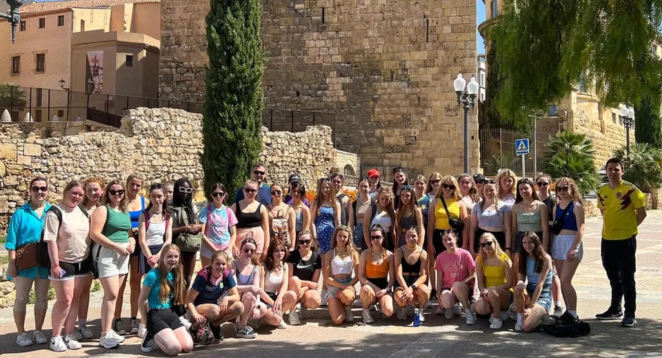 Un grande gruppo di studenti nell'area esterna della Eureka Secondary School davanti a storici edifici in pietra e spazi verdi.