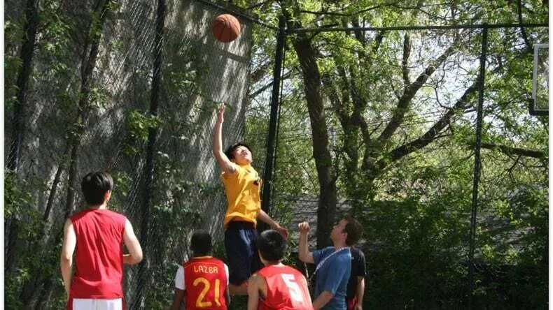 Estudiantes del Great Lakes College of Toronto juegan al baloncesto en una zona arbolada del campus.