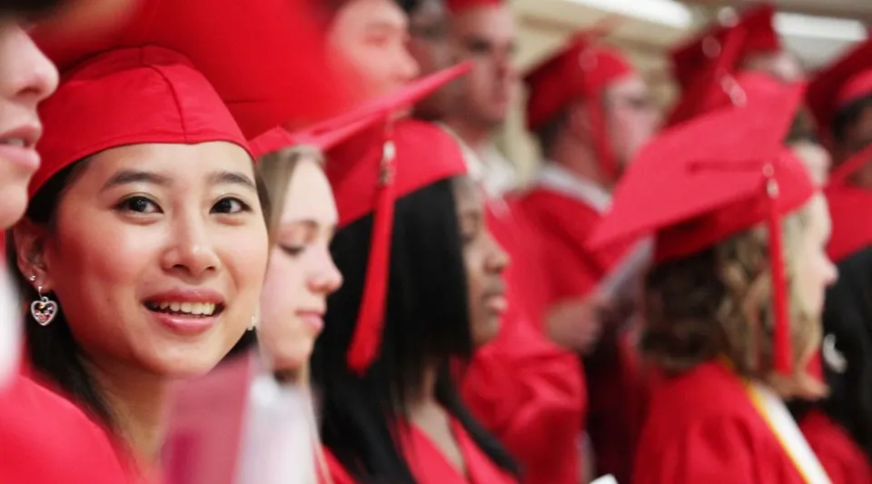 Studenti della St. Croix Lutheran Academy indossano toghe rosse e festeggiano il loro diploma.