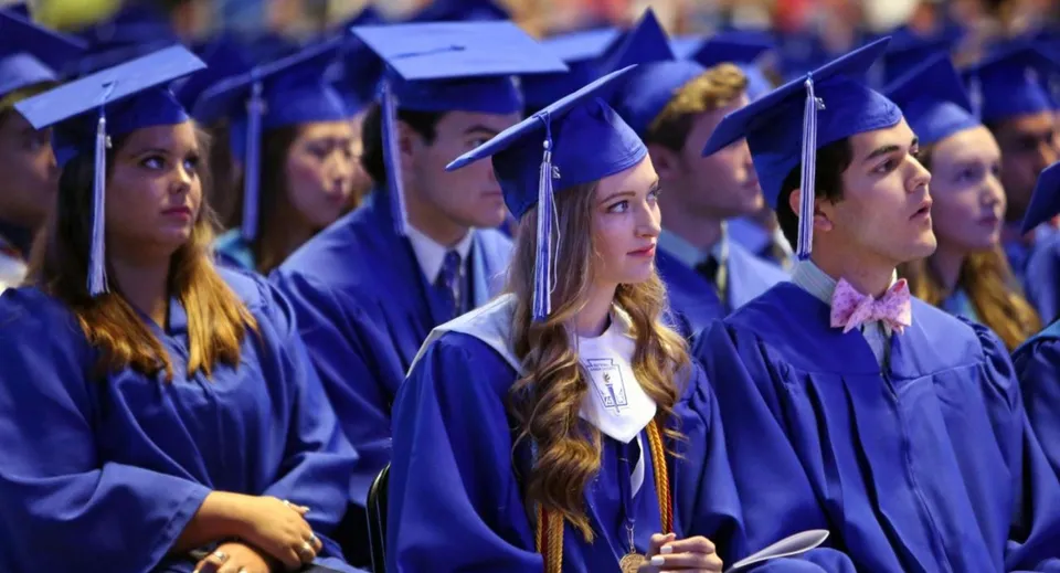 Un gruppo di diplomati in toga blu sta insieme alla cerimonia di diploma della Bell High School.