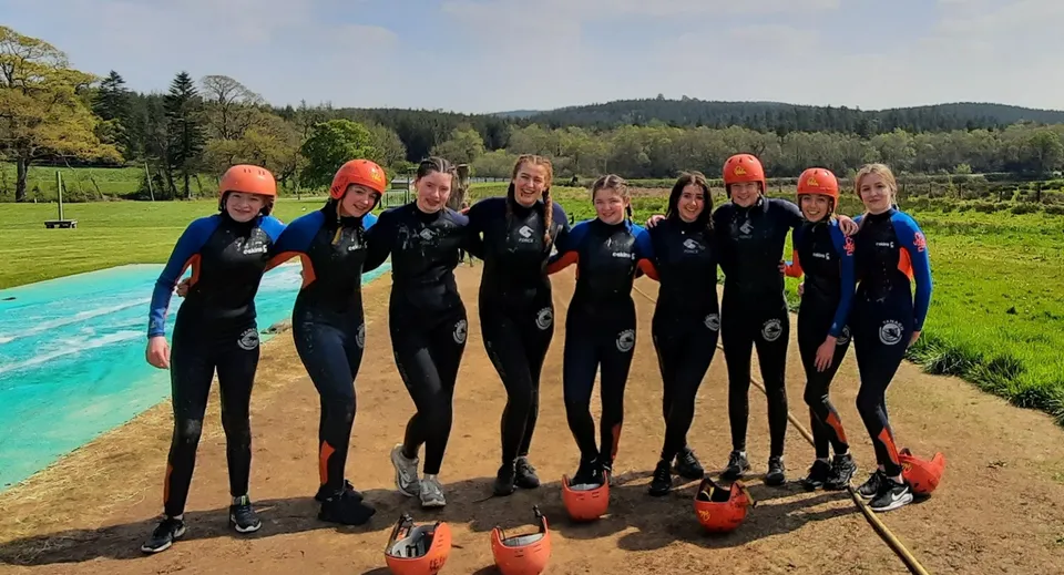 Studenti dell'O’Carolan College indossano mute in neoprene e caschi durante un'attività di sport acquatici all'aperto.