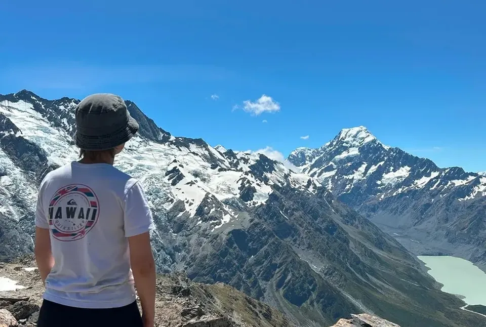 Louisa blickt von hinten auf die schneebedeckten Berge Neuseelands