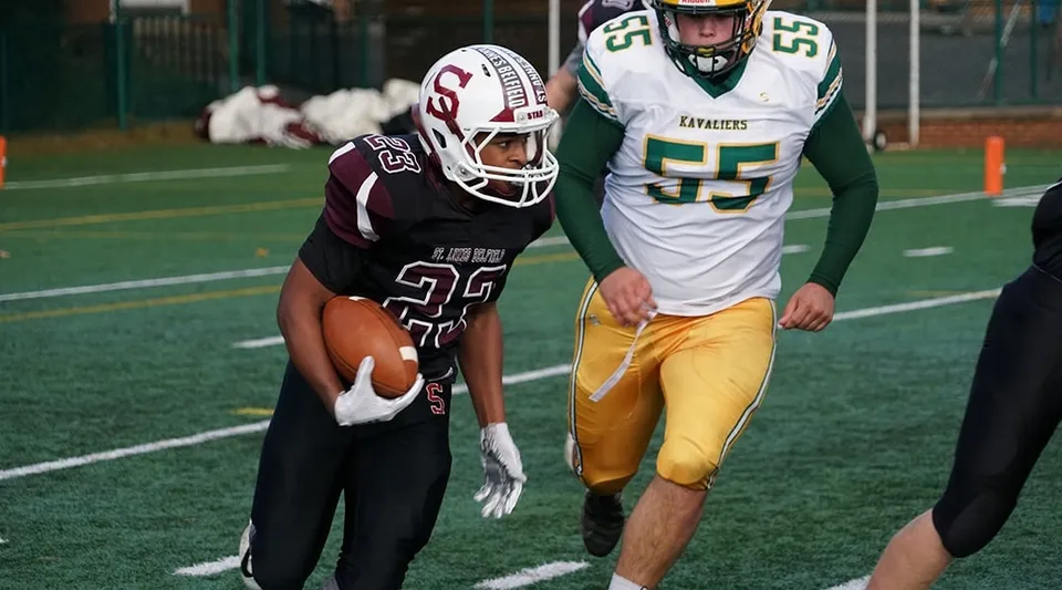 Due giocatori di football sul campo della St. Anne's-Belfield School lottano per la palla davanti alla porta.