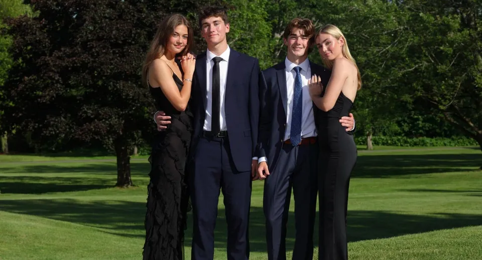 Quattro studenti della Fulford Academy posano su un prato davanti agli alberi.