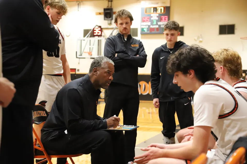 Un allenatore di pallacanestro della Gladstone High School parla con la sua squadra durante un timeout in palestra.