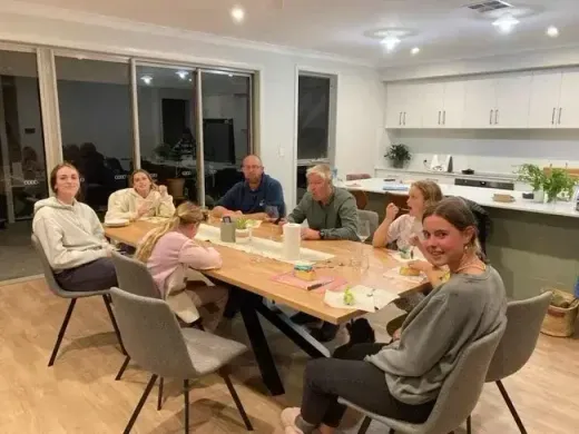 Famiglia ospitante e studenti seduti la sera attorno al tavolo da pranzo di casa