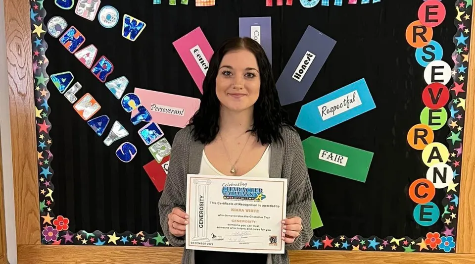 Una studentessa della Seaway District High School mostra un certificato davanti a una bacheca decorata.