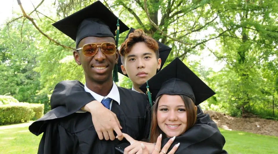 Tre diplomati della Oakwood Friends School posano insieme nell'area verde esterna.
