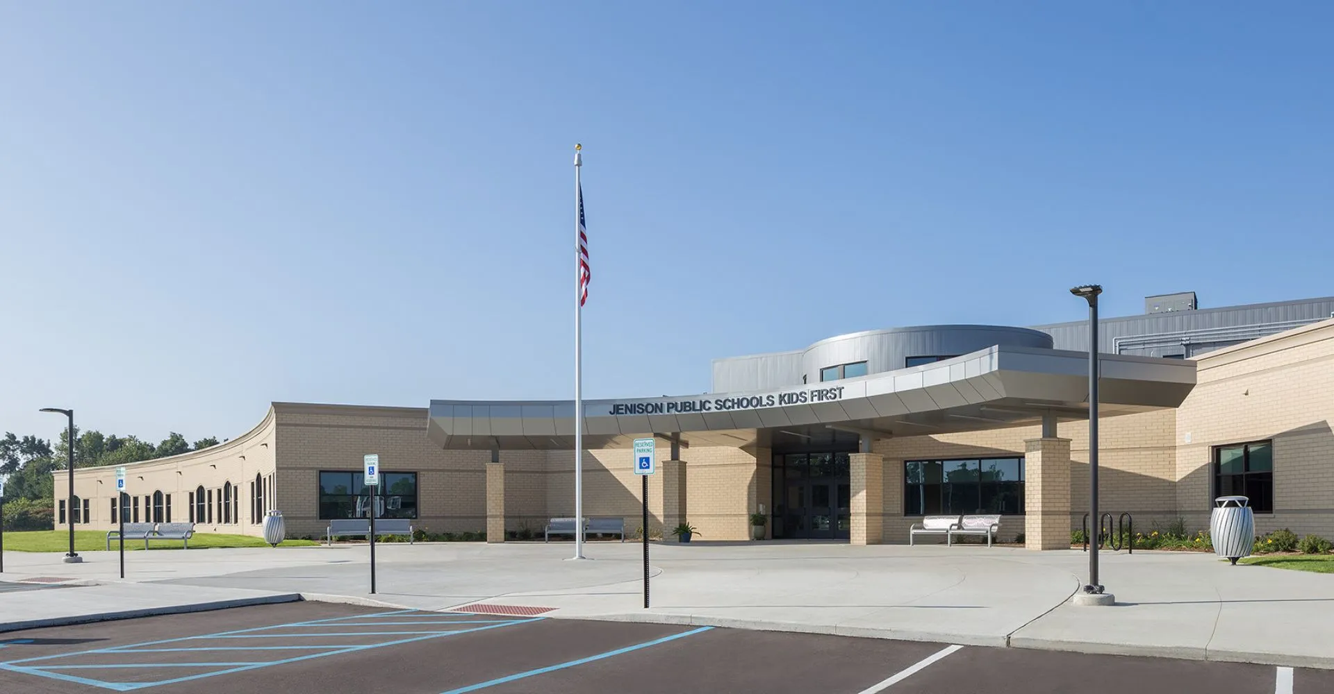 L'edificio moderno con tetto curvo e bandiera americana davanti alle Jenison Public Schools.