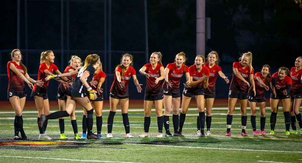 Un gruppo di calciatrici in maglia rossa si trova sul campo da gioco della Santiam Christian School.