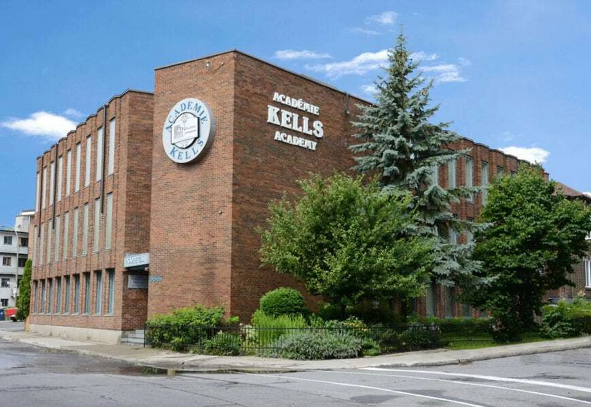 L'imponente edificio in mattoni con la torre dell'orologio nel campus della Kells Academy è circondato da alberi e spazi verdi.