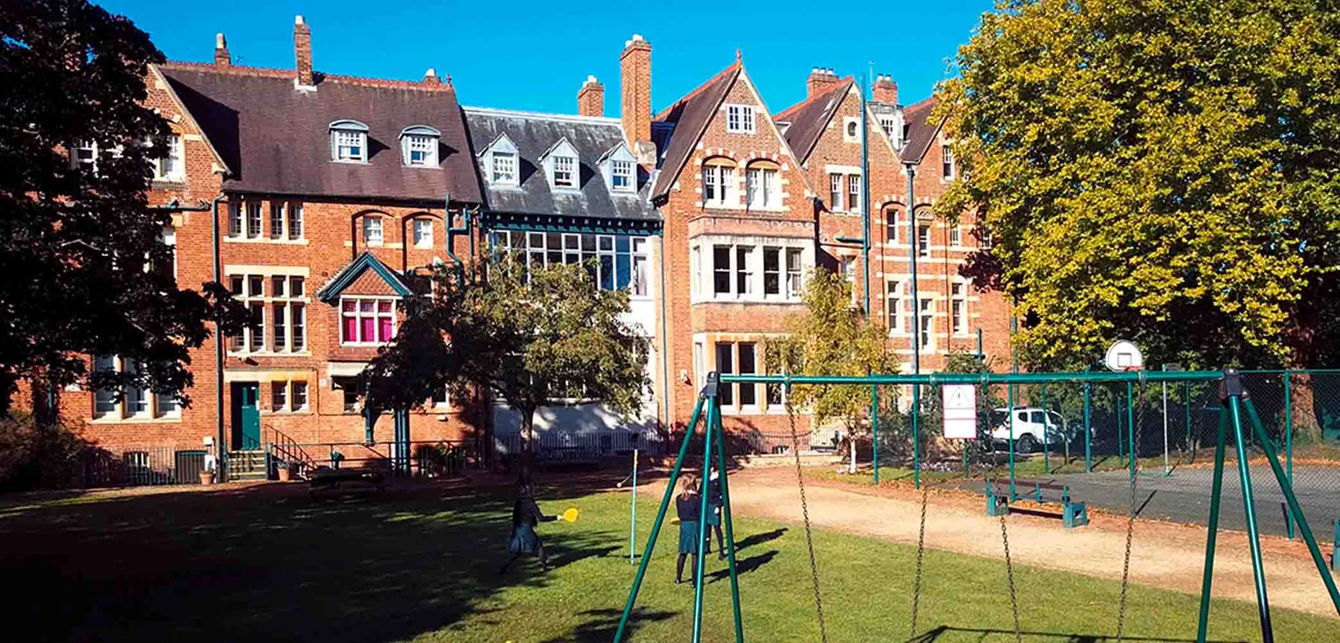 L'edificio storico in mattoni rossi della Wychwood School con un cortile dove giocano alcune studentesse.