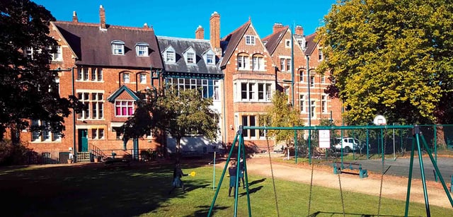 L'edificio storico in mattoni rossi della Wychwood School con un cortile dove giocano alcune studentesse.
