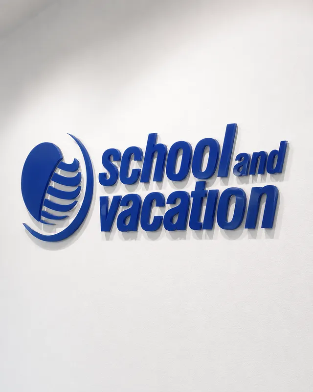 Logo di School and Vacation in rilievo blu su una parete bianca