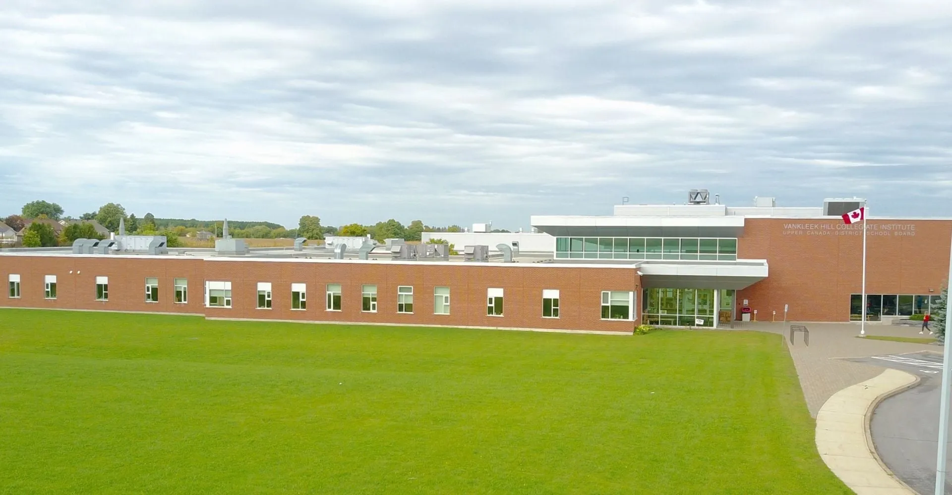 L'edificio in mattoni a più piani con grandi finestre del Vankleek Hill Collegiate Institute si trova su un prato circondato da alberi.