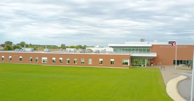 L'edificio in mattoni a più piani con grandi finestre del Vankleek Hill Collegiate Institute si trova su un prato circondato da alberi.