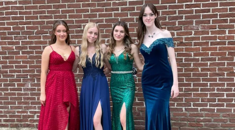 Quattro studentesse in abito formale si trovano davanti a una parete di mattoni all'interno del campus della Chateauguay Valley Regional High School.