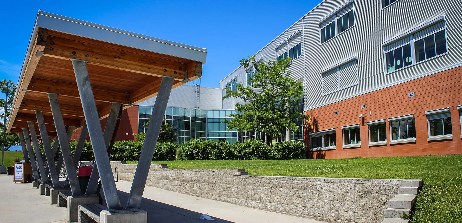 L'edificio moderno della Vernon Secondary School con sporgenza in legno e vetrate è circondato da un prato con scalinate in pietra.