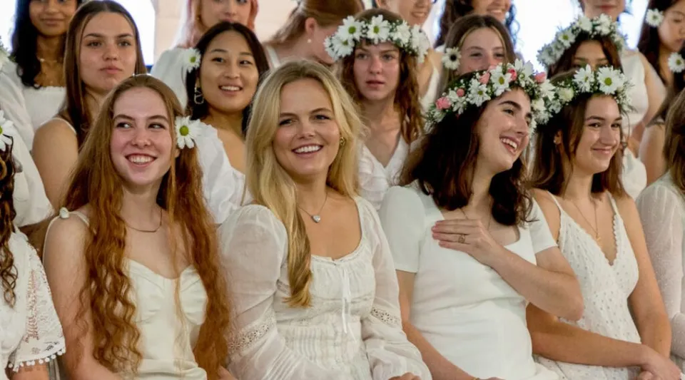 Studentesse della Miss Porter's School indossano abiti bianchi e corone di fiori tra i capelli.