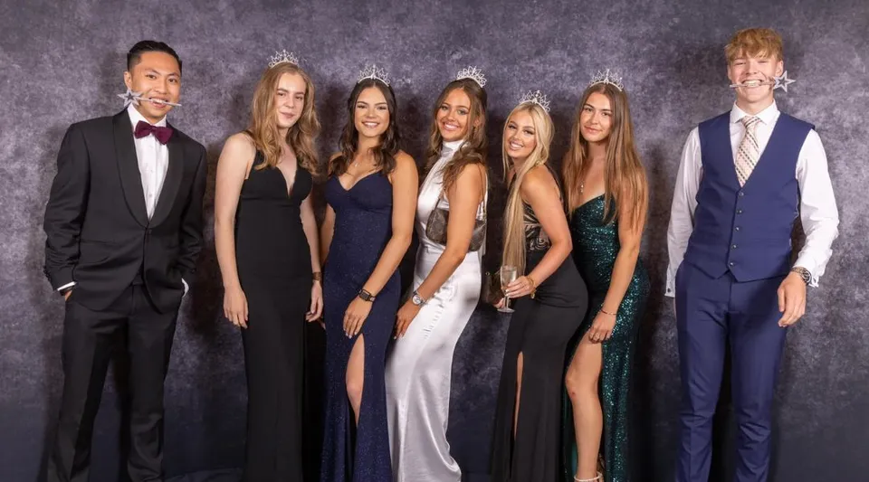 Un gruppo di persone in abito formale posa davanti a uno sfondo scuro nella foto della St. Dominic's Grammar School.