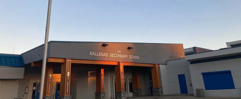 L'edificio moderno della Ballenas Secondary School con un cartello ben visibile contro un cielo blu limpido.