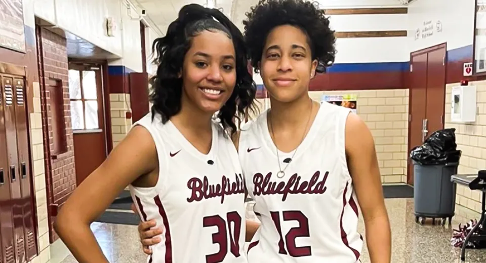 Due studentesse in canotta da basket della Bluefield High School insieme nel corridoio della scuola.