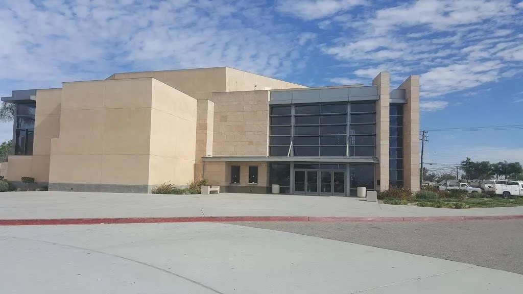 El moderno edificio de varios pisos de la John F. Kennedy High School se encuentra frente a un cielo azul con pocas nubes.