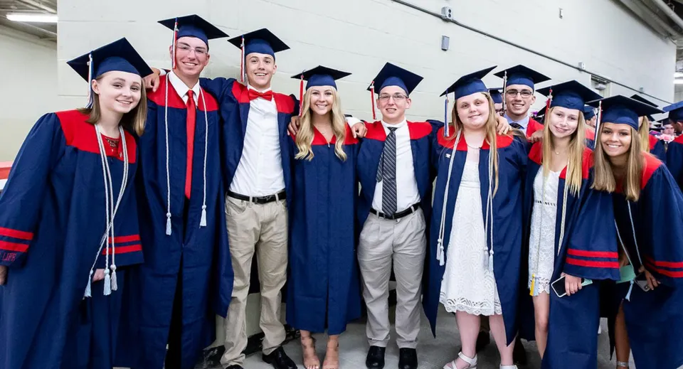 Un gruppo di diplomati della Brisbane State High School festeggia il proprio diploma nel corridoio indossando le loro toghe rosse e blu.