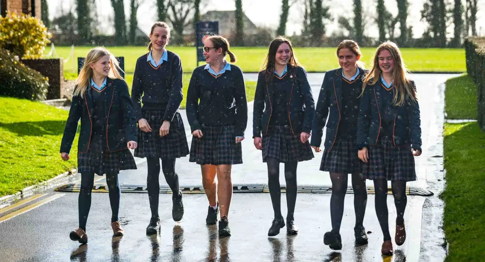 Sei studentesse in uniforme della St. Swithun's School camminano insieme nel campus.