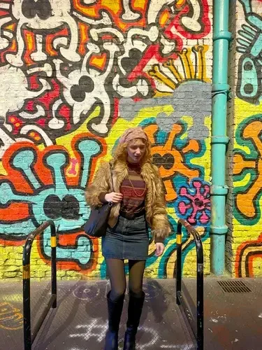 Chica posando ante un muro cubierto de grafitis de colores