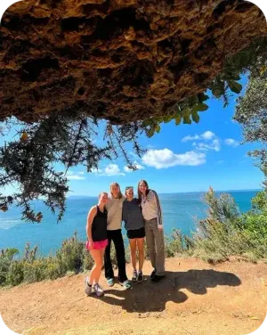 Quattro ragazze posano su un promontorio roccioso affacciato sul mare in Nuova Zelanda