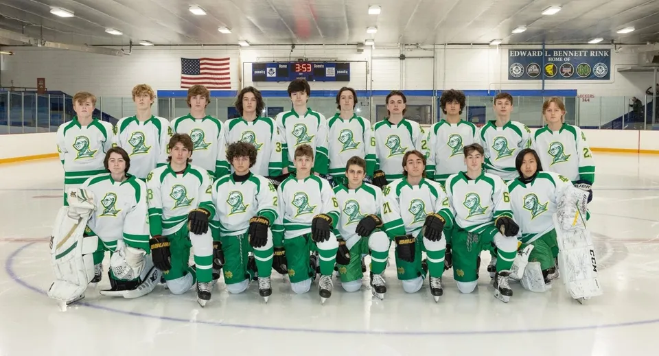 Un gruppo di giovani giocatori e giocatrici di hockey posa sulla pista da ghiaccio del campus della Notre Dame de la Baie Academy.