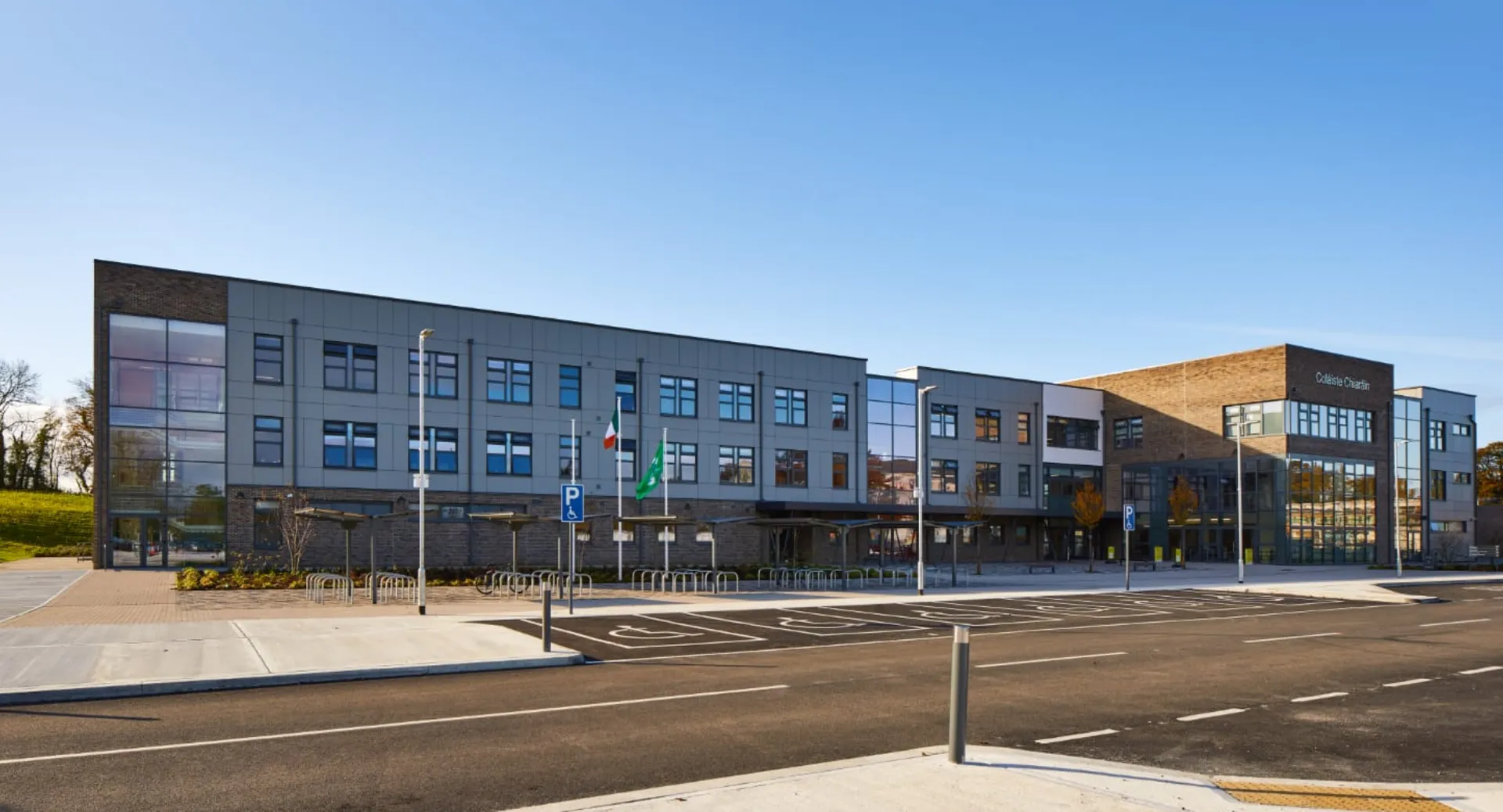 L'edificio moderno a più piani del Colaiste Chiarain Athlone con facciate in vetro e parcheggio sotto un cielo azzurro.