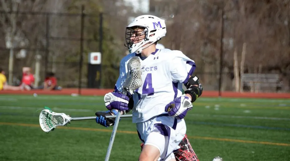 Un giocatore di lacrosse con il numero 4 in divisa bianca sul campo sportivo di The Masters School.