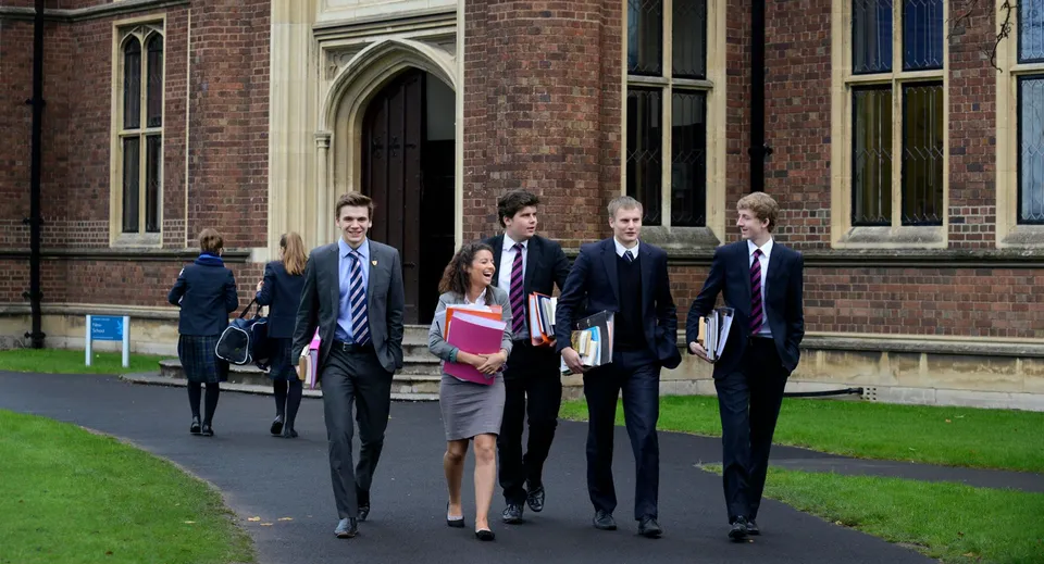 Un gruppo di studenti cammina insieme nel campus del Wrekin College passando accanto a un edificio in mattoni e a un'area verde.