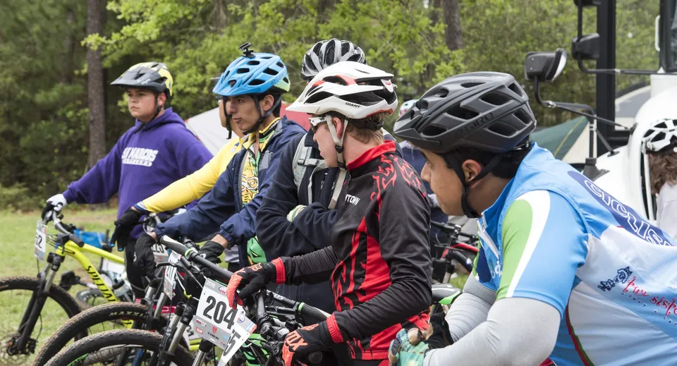 Un gruppo di studenti della Bush Post Primary School in un bosco con biciclette e abbigliamento protettivo.
