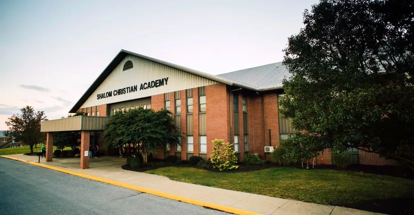 L'edificio in mattoni a due piani della Shalom Christian Academy è circondato da alberi e prati.