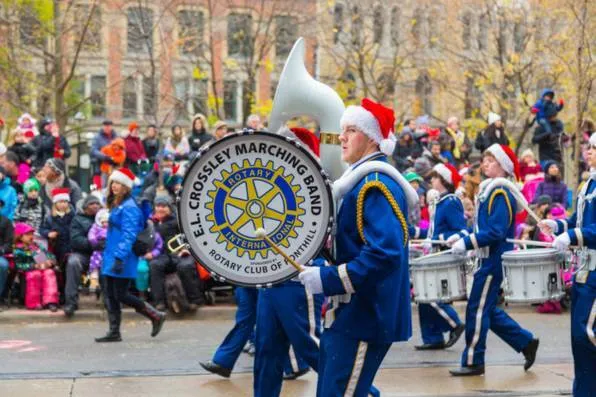 Banda de música con uniformes azules y gorros de Papá Noel desfilando ante el público