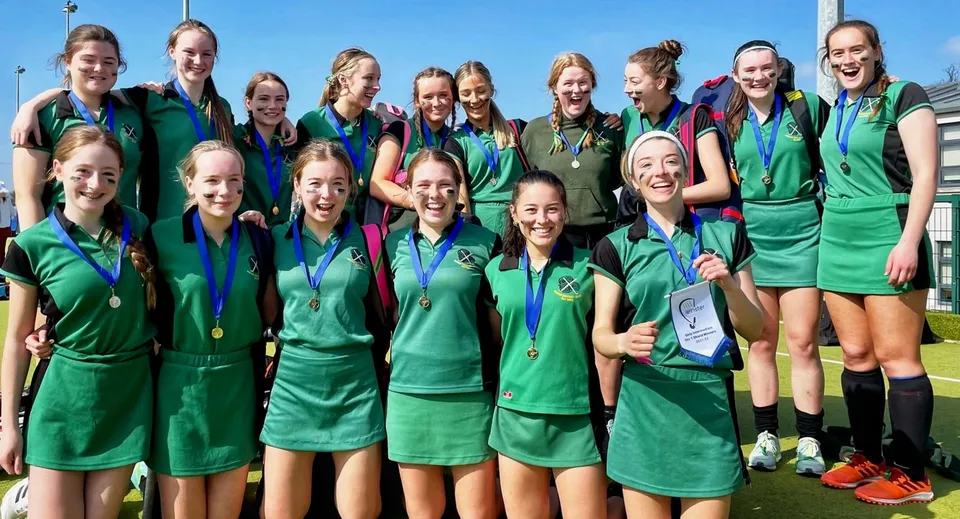Un gruppo di giovani atlete della St. Vincent's Secondary School festeggia insieme il proprio successo sotto un cielo azzurro e limpido.