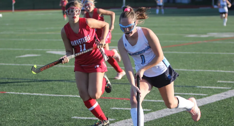 Due studentesse della Scoil Mhuire Cork giocano una partita di hockey di notte sul campo da gioco.